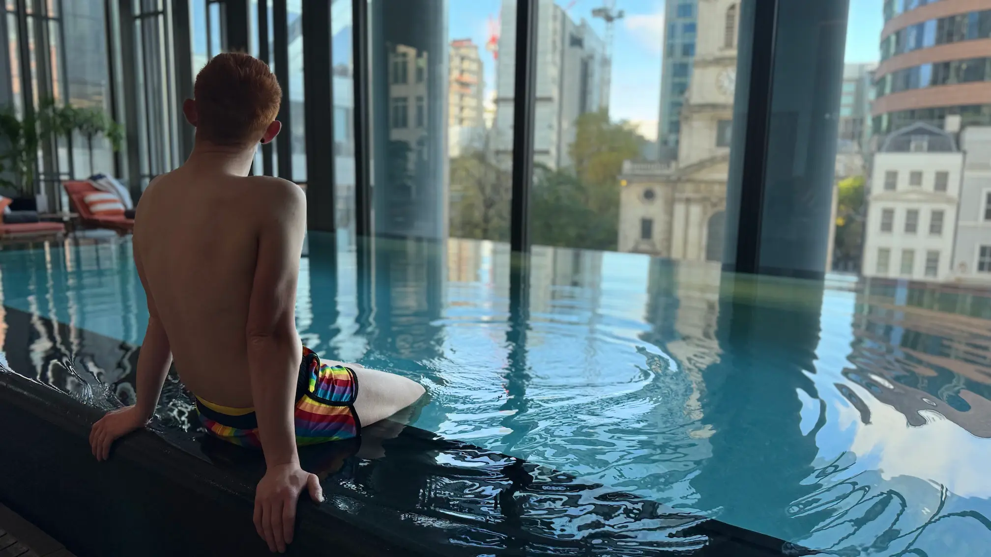Alex relaxing by the pool at Pan Pacific London Hotel, enjoying luxury city views and stylish LGBTQ+ friendly accommodation.